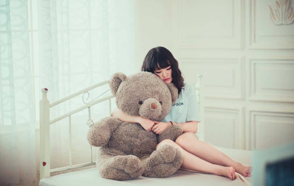 Woman on the bed holding a teddy bear