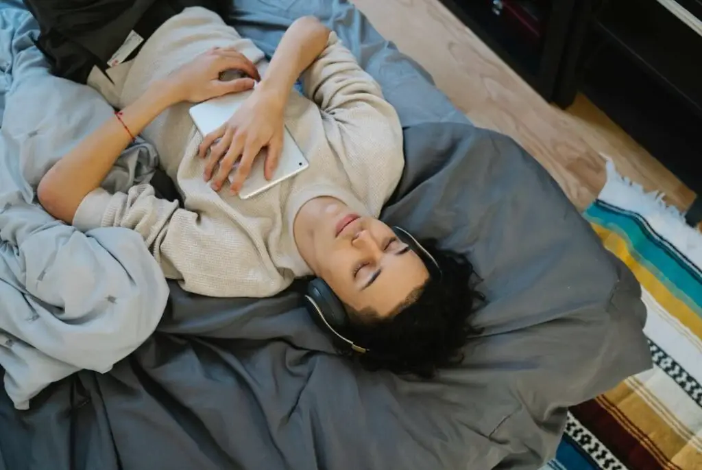 Man wearing headphones lying in bed listening to music