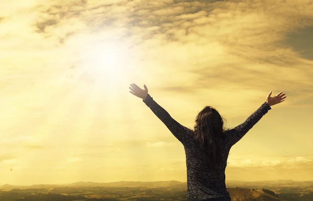 Woman facing the sky with raised hands