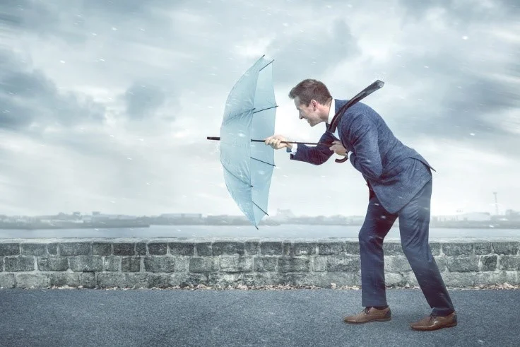 Man in suit holding an umbrella against strong wind