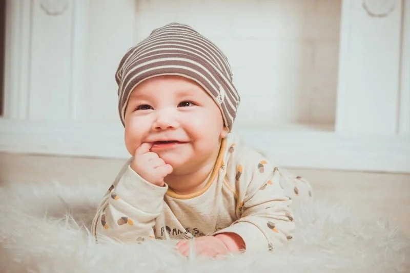 Smiling baby with a finger in the mouth