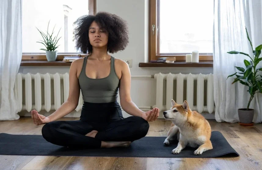 Woman in a meditative pose beside her dog