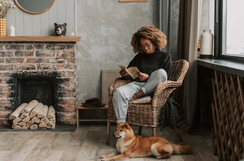 Woman reading with her dog resting at her feet